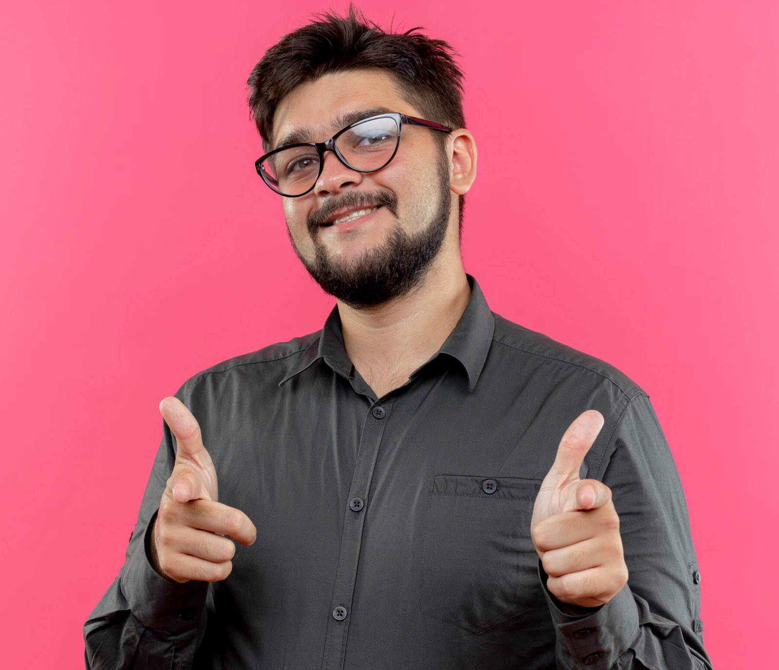 pleased young businessman wearing glasses showing you gestures isolated on pink background